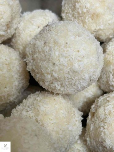 Freshly rolled coconut ladoo balls coated in desiccated coconut on a plate, a classic Indian Foods festival sweet